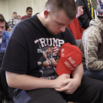 Young men with MAGA hats praying