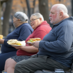 Obese People holding full plates on park bench.png