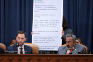 Rep. Jason Crow (D., Colo), left, speaks in front of a display of Defense Secretary Pete Hegseth’s Signal messages