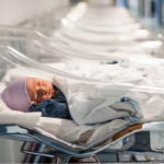 Newborn in isolet in row of empty isolets