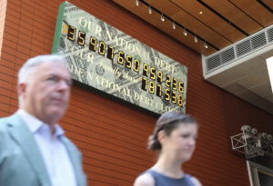 Pedestrians walk past the National Debt Clock in New York on June 4.