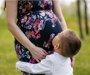 Little boy hugs pregnant mommy's legs