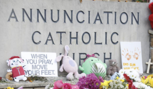 memorial gifts left at Annuciation Catholic Church sign following shooting